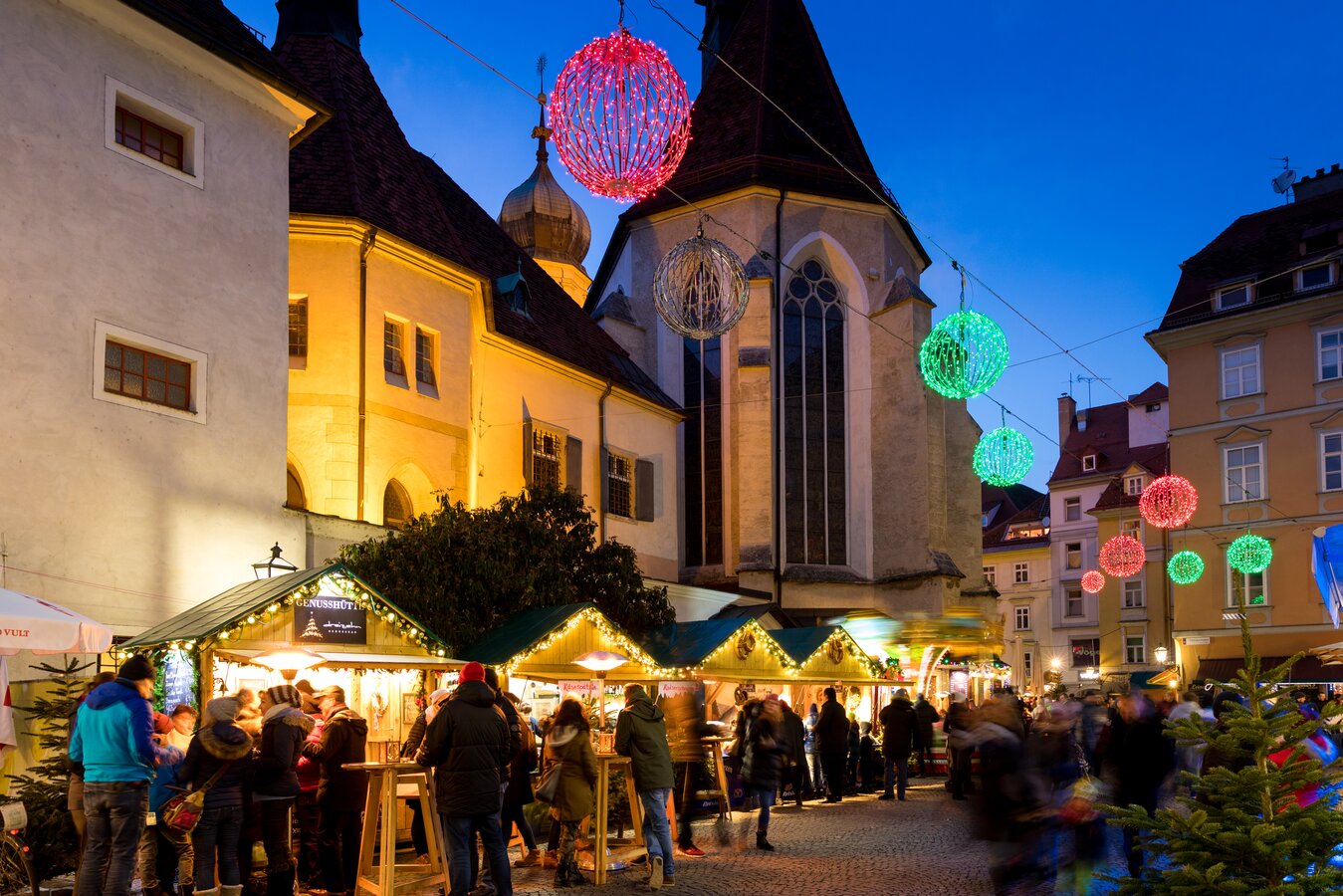 Graz Christmas market at dusk with colorful sphere lights.