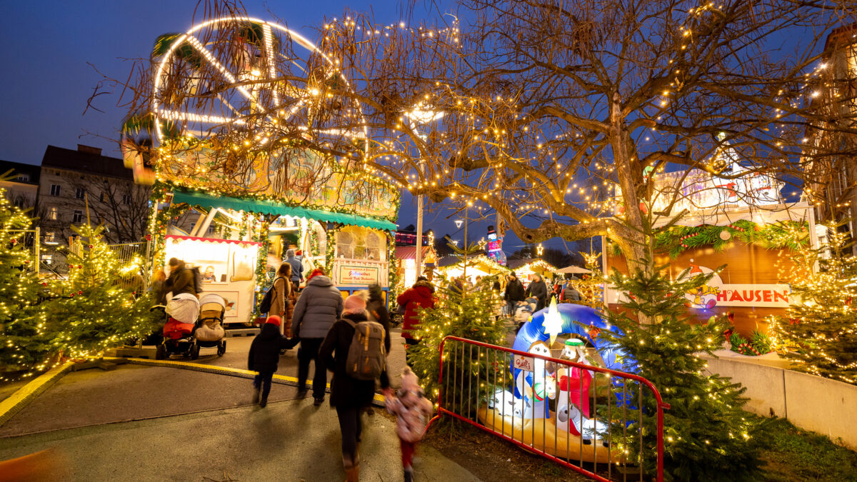 Weihnachtsmarkt Graz mit beleuchtetem Riesenrad und Menschen.