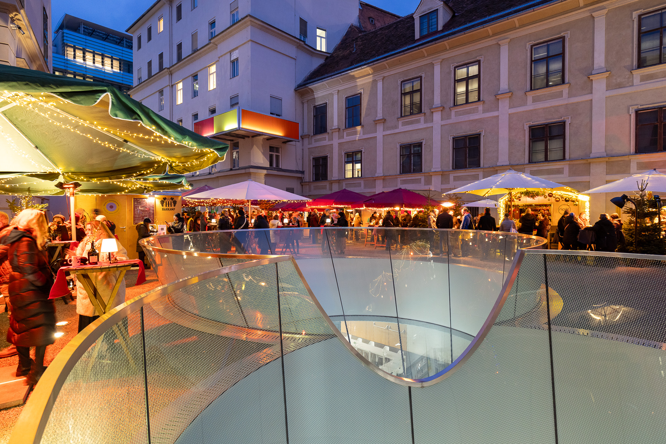 Night view of Graz Christmas market from spiral staircase. Umbrellas and lights.