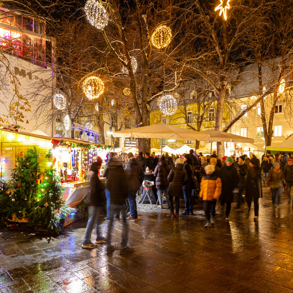 Weihnachtsmarkt am Abend in Graz mit beleuchteten Ständen und Menschen.