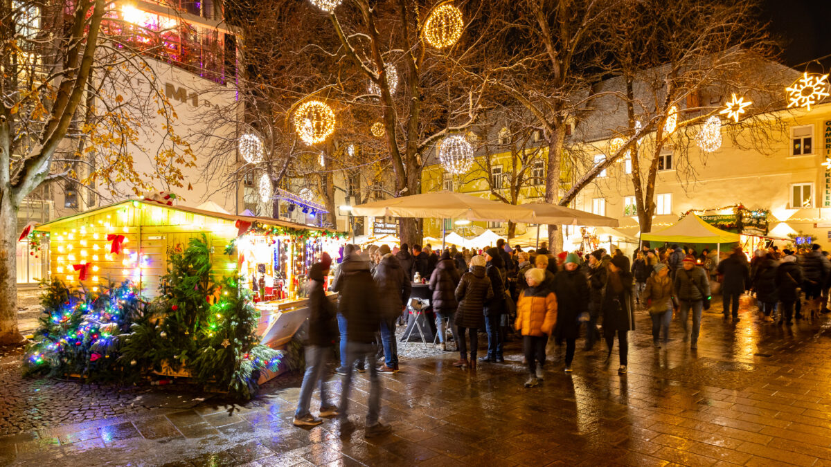 Weihnachtsmarkt am Abend in Graz mit beleuchteten Ständen und Menschen.