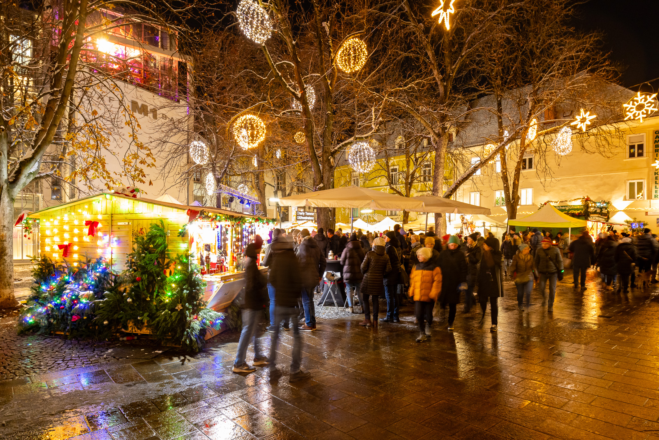 Weihnachtsmarkt am Abend in Graz mit beleuchteten Ständen und Menschen.