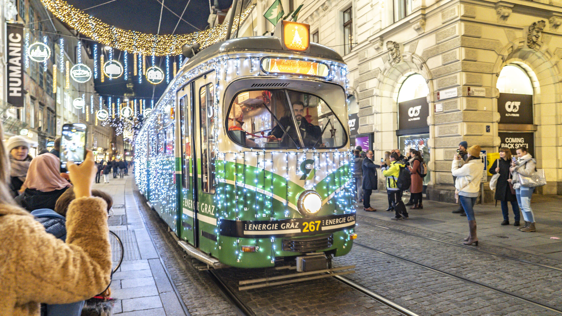 Adventbim: A decorated tram, number 267, drives through Graz. Crowds watch.