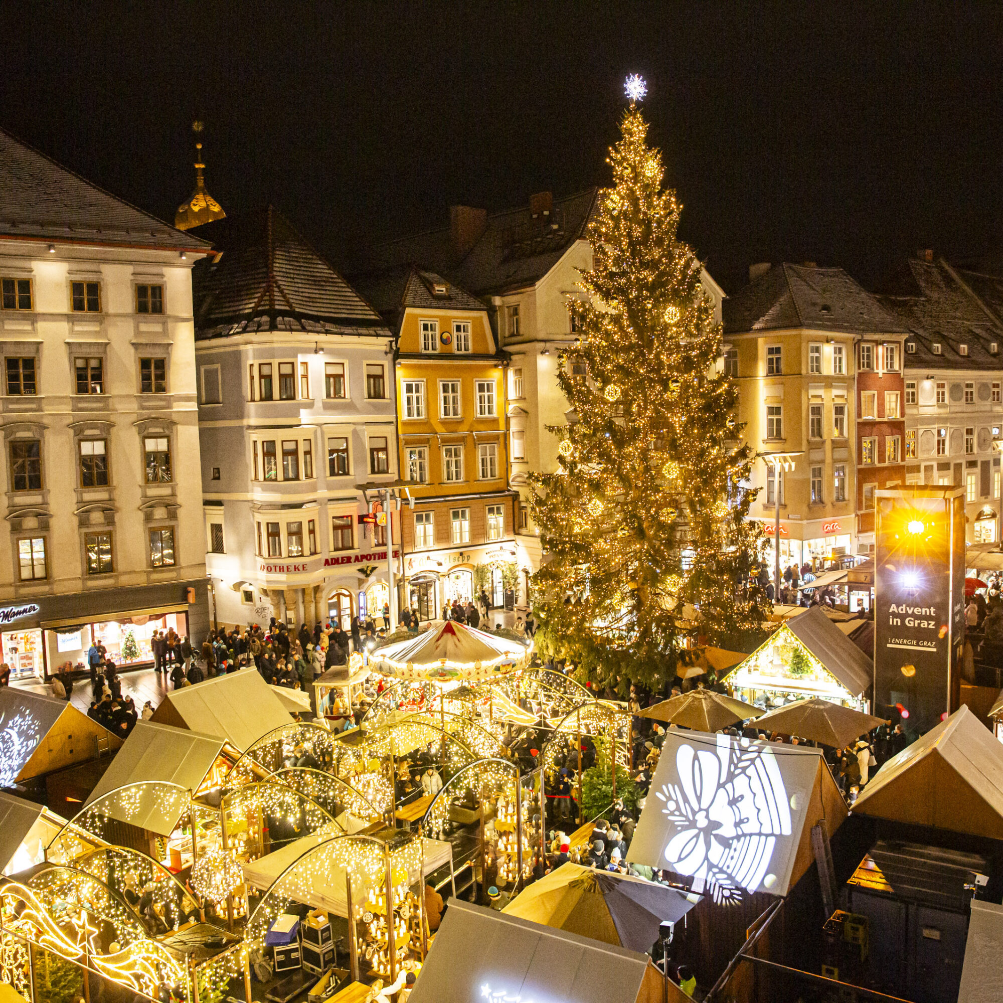 Luftaufnahme des Weihnachtsmarktes in Graz mit Weihnachtsbaum und Buden.