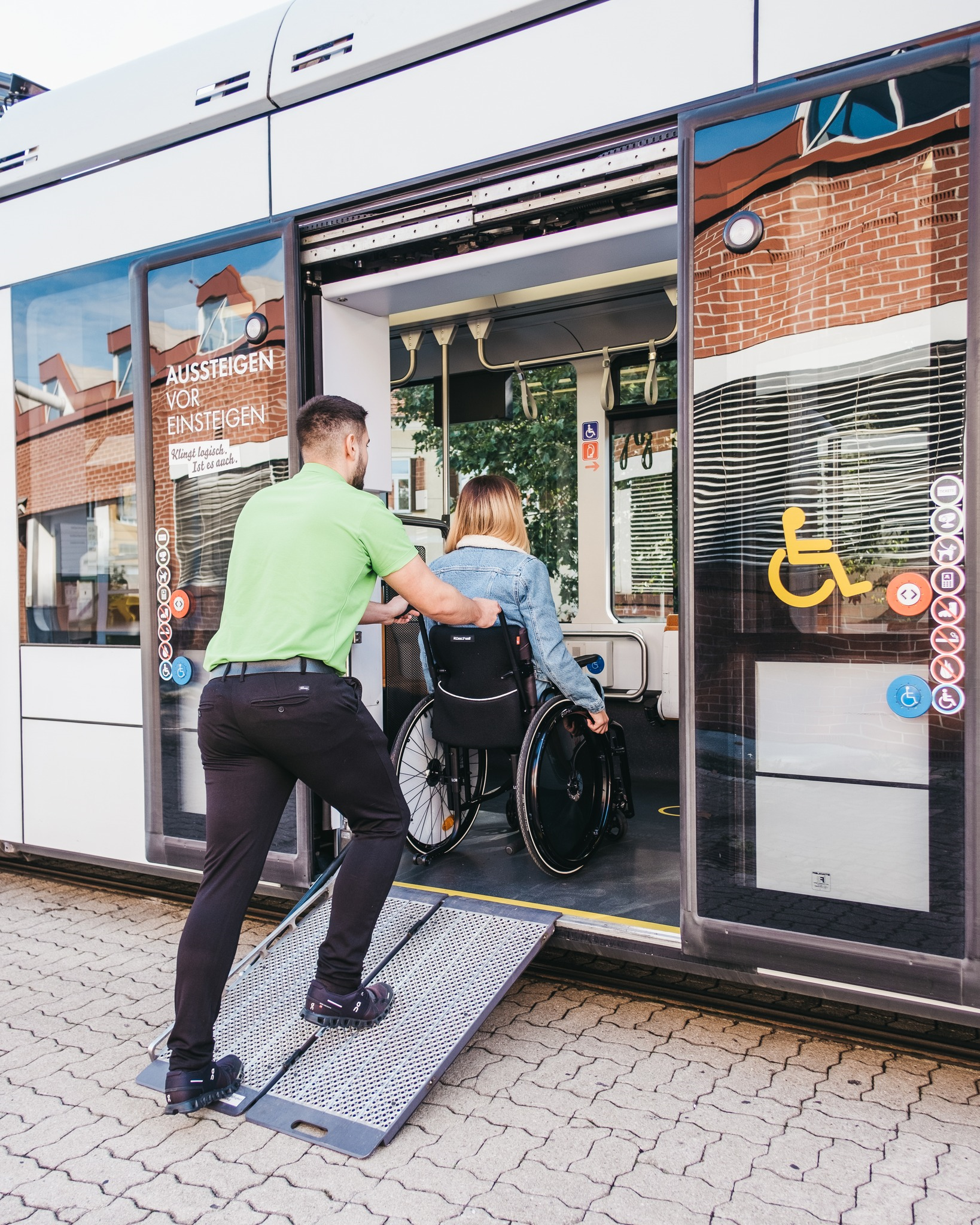 Fahrer der Graz Linien schiebt Frau in Rollstuhl über Rampe in eine Straßenbahn