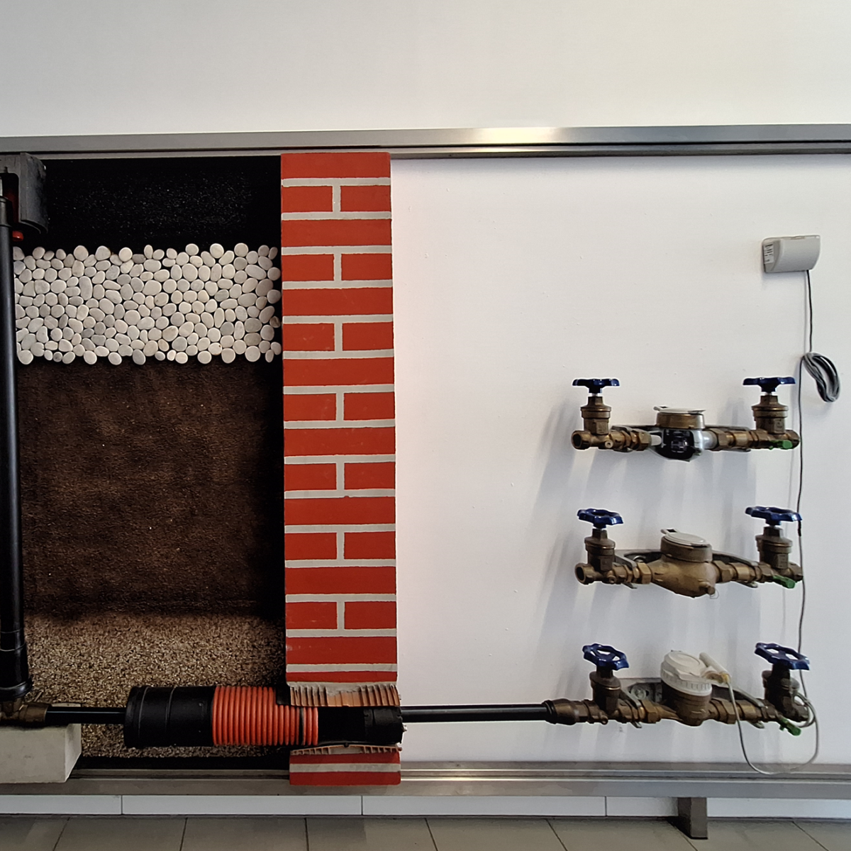 Diagramm eines Rohrsystems durch Boden, Ziegel und Wasserzähler.