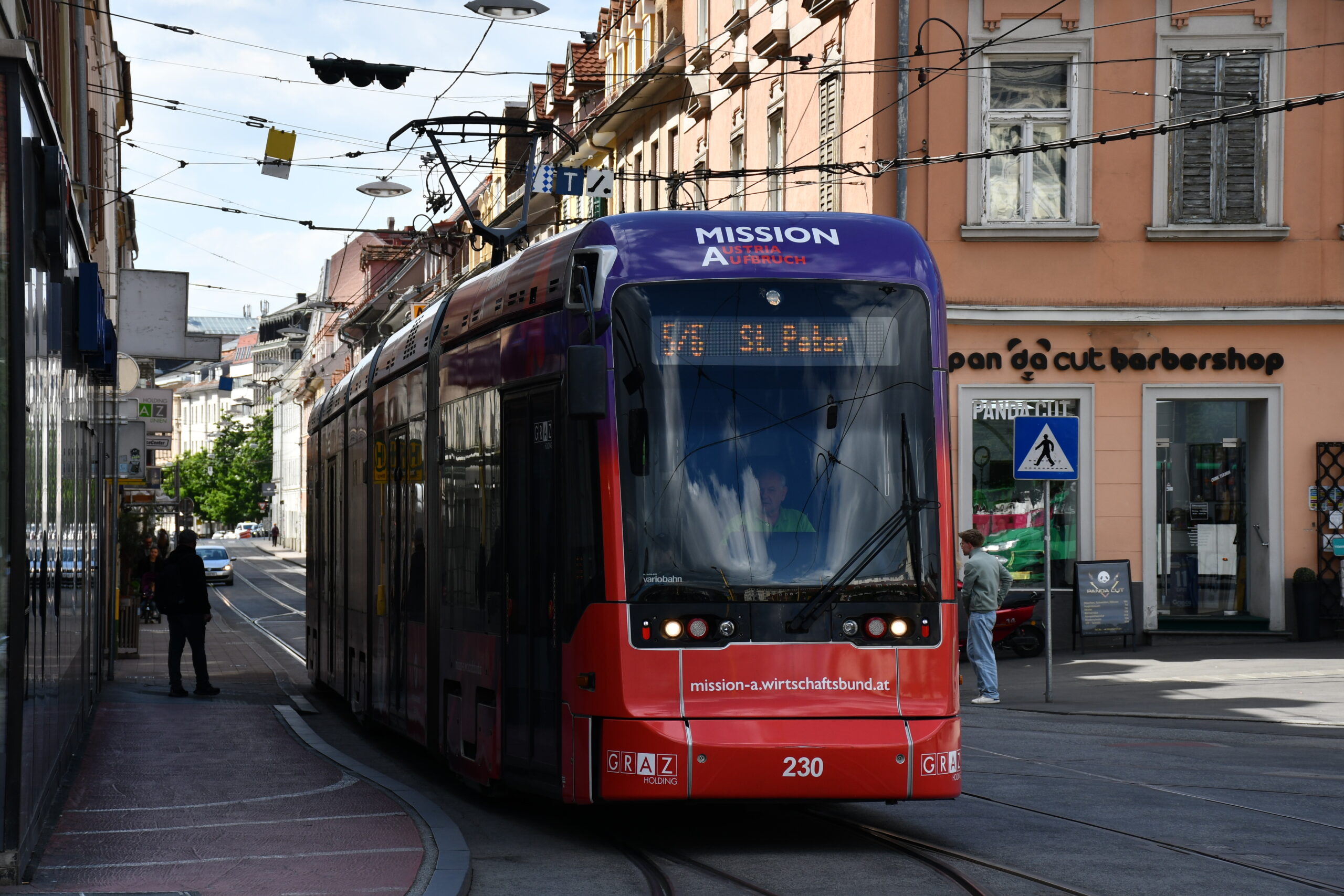 Eine rote und lila Straßenbahn "Mission A" (Linie 5/6 St. Peter) in Graz.