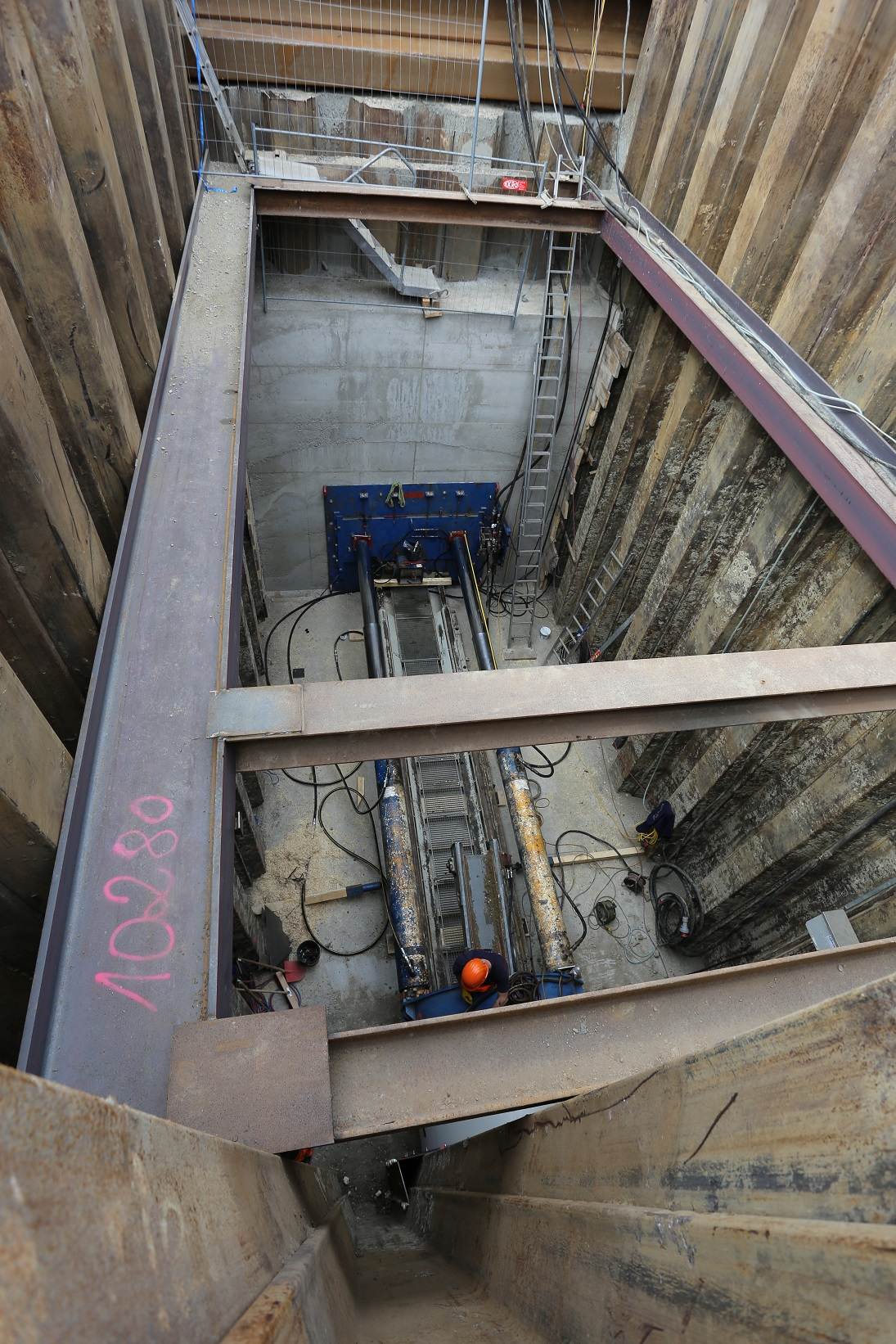 Tiefe Baugrube in Graz mit Stahlträgern und Bauarbeitern. "10280" sichtbar.