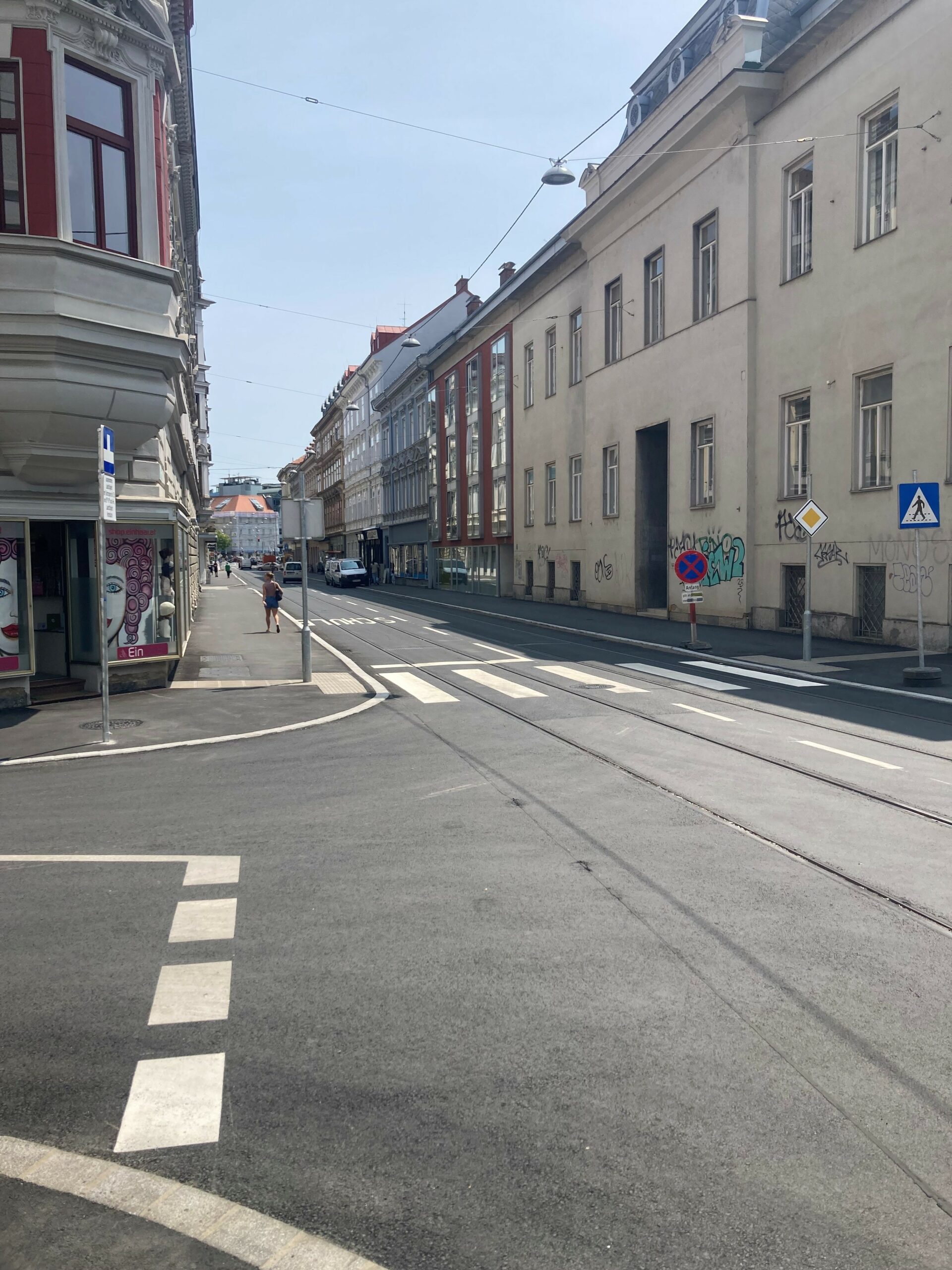 Eine Straßenansicht in Graz mit Gebäuden und Straßenmarkierungen.