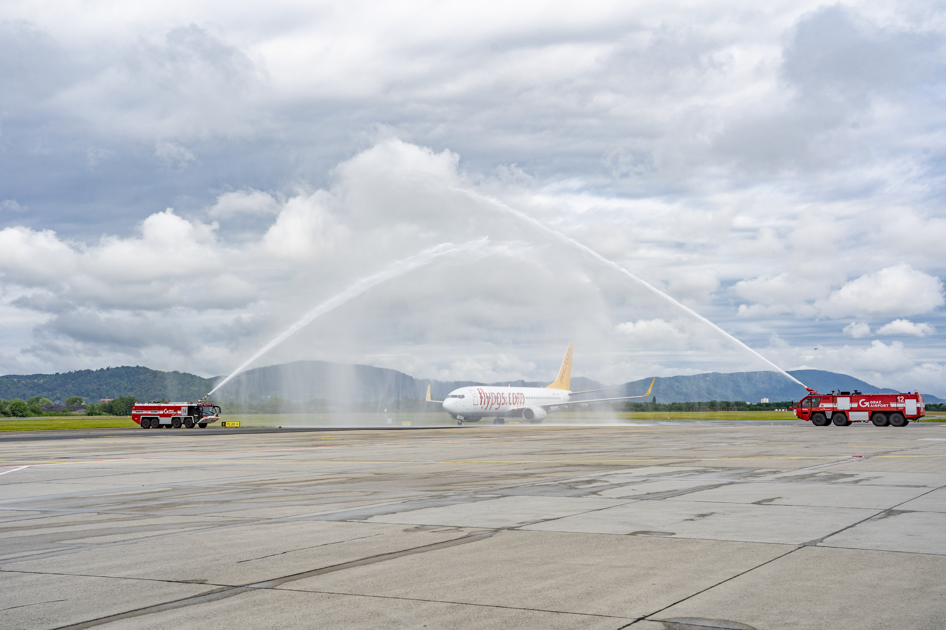Ein "Pegasus"-Flugzeug in Graz wird von Feuerwehrfahrzeugen begrüßt.