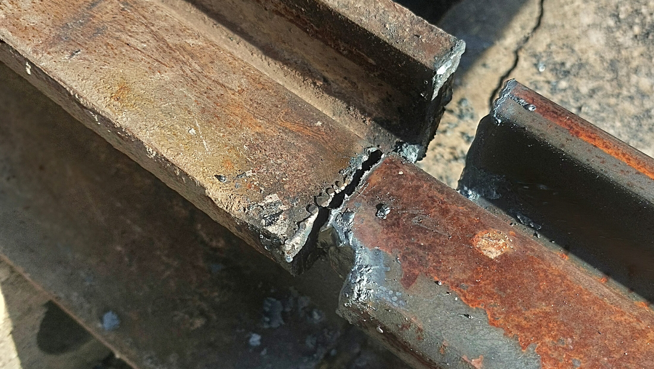 Zwei zusammengeschweißte, rostige Schienen.