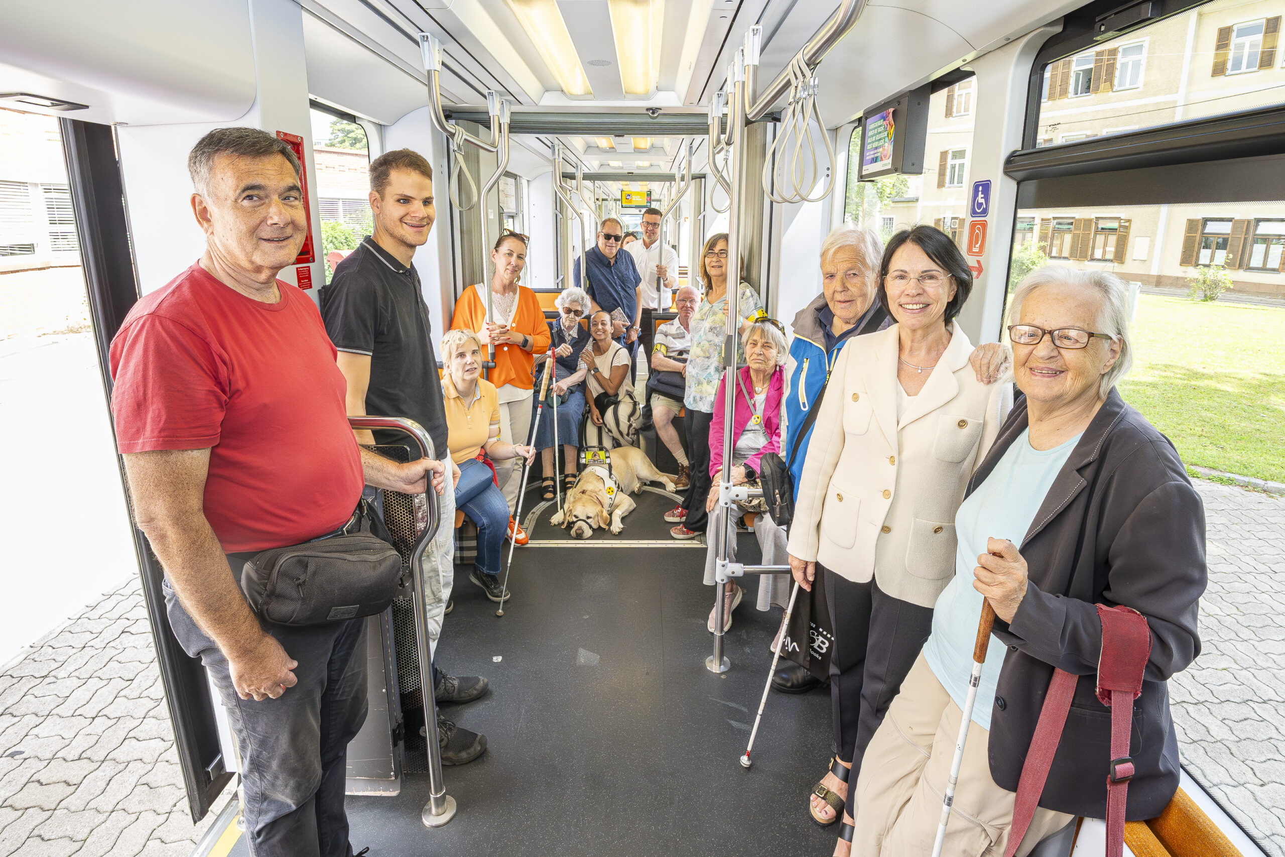 Seniorengruppe mit Blindenhund in Straßenbahn in Graz.