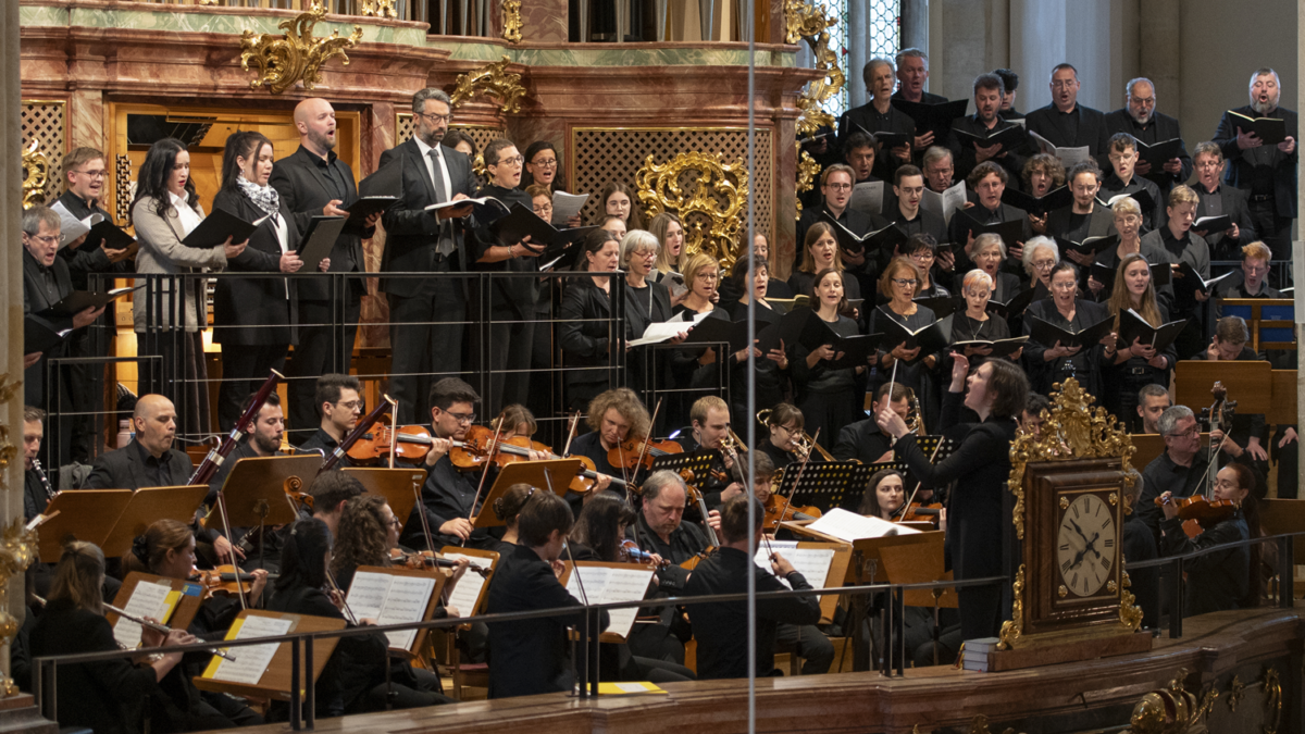 Chor und Orchester treten in Graz in einem verzierten Raum auf.