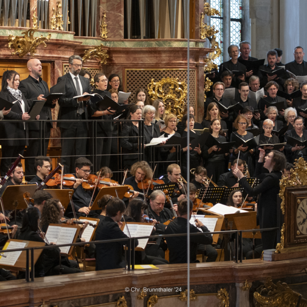 Chor und Orchester treten in Graz in einem verzierten Raum auf.