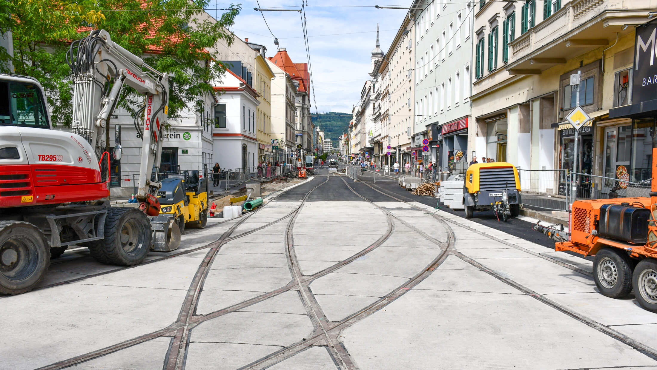 Straßenbauarbeiten in Graz. Straßenbahnschienen und Baumaschinen.