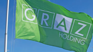 Grüne Flagge der Holding Graz vor blauem Himmel.