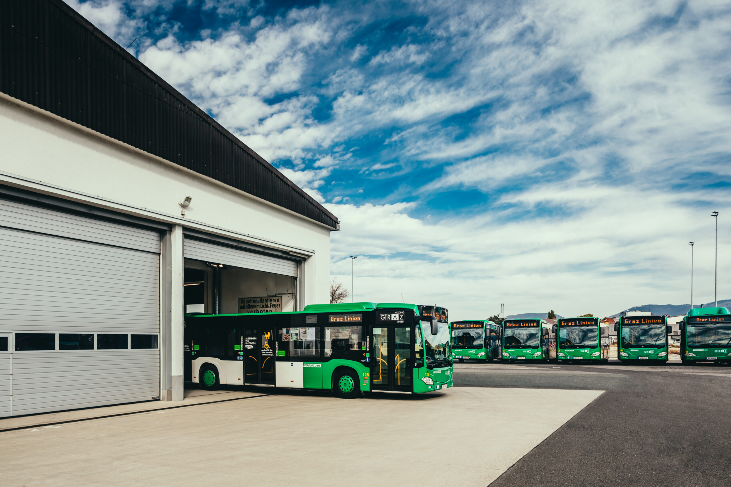 Grüne Graz Linien Busse stehen vor einer Garage.