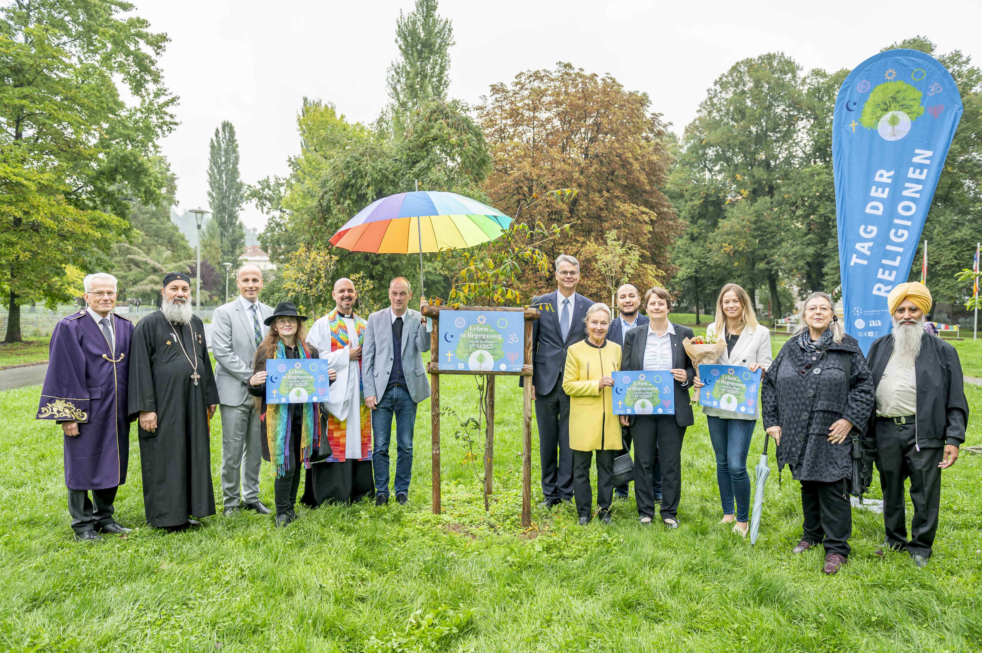 Eine Gruppe von Menschen posiert mit Schildern "Leben in Begegnung" in Graz.