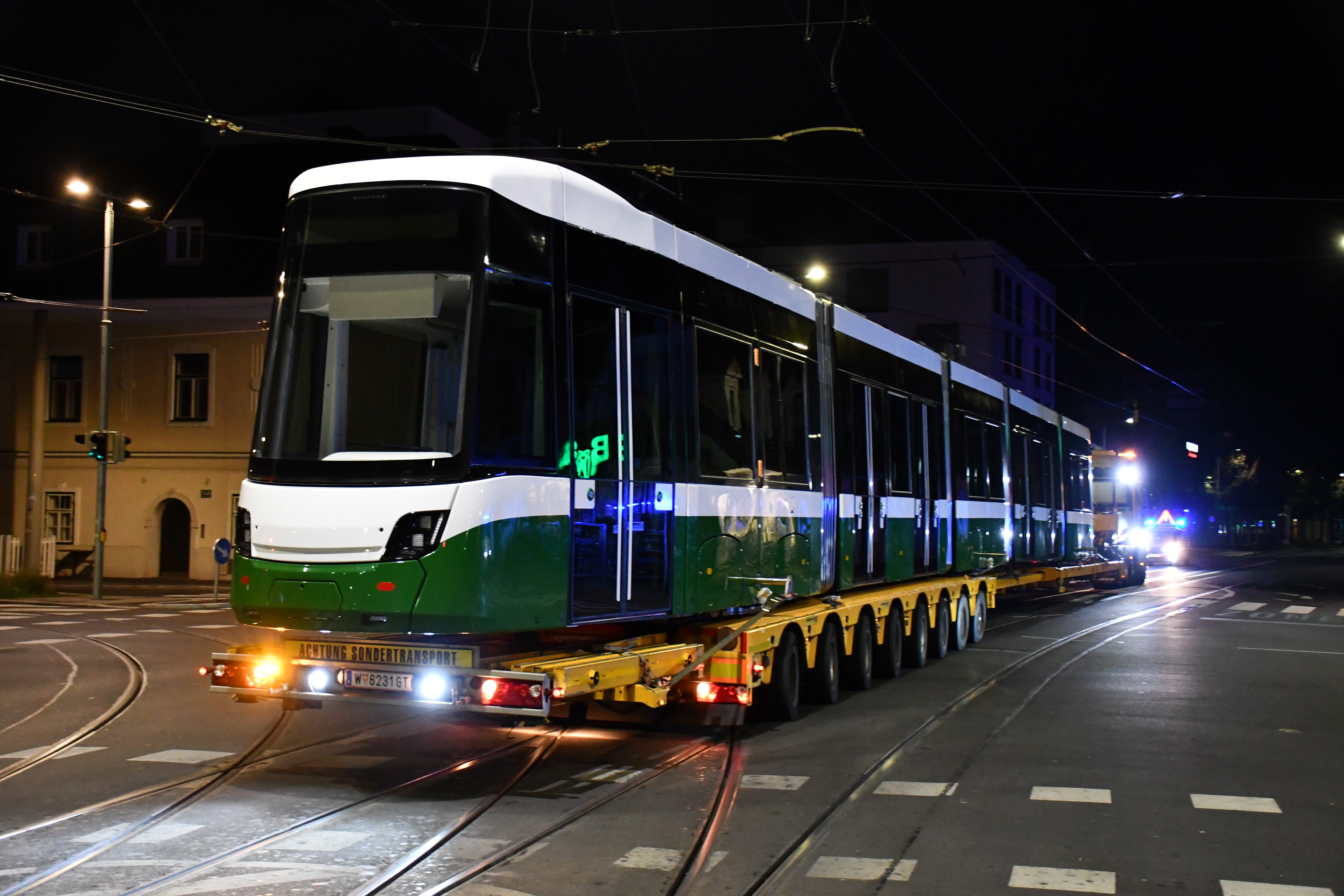 Eine Straßenbahn in Graz auf einem Tieflader bei Nacht. "ACHTUNG SONDERTRANSPORT"