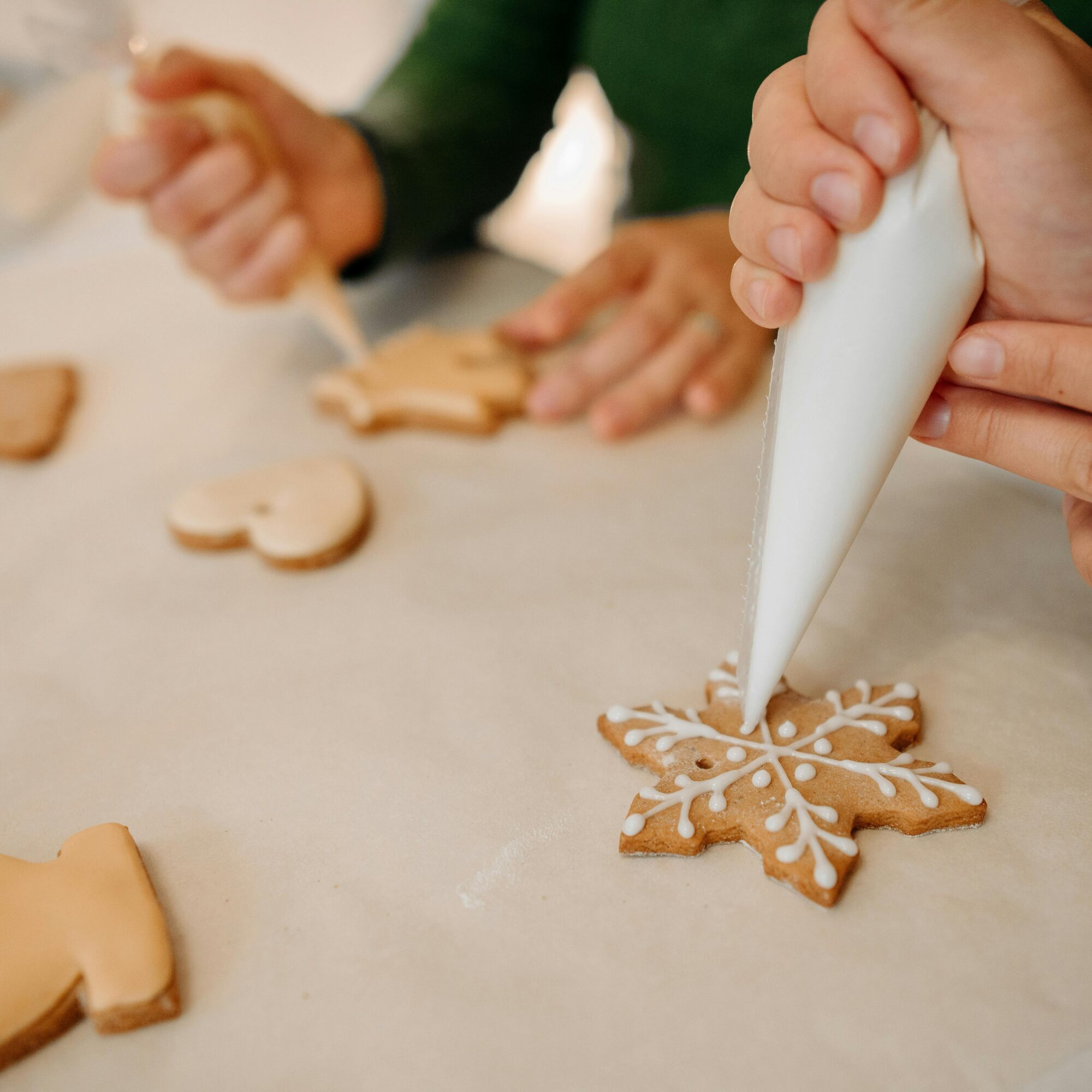 Zwei Personen verzieren Lebkuchen mit weißem Zuckerguss.