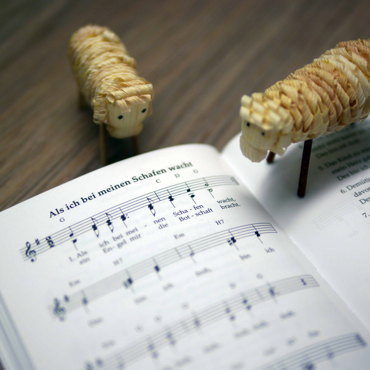 Zwei Schaf-Figuren und ein aufgeschlagenes Notenblatt. "Als ich bei meinen Schafen wacht".