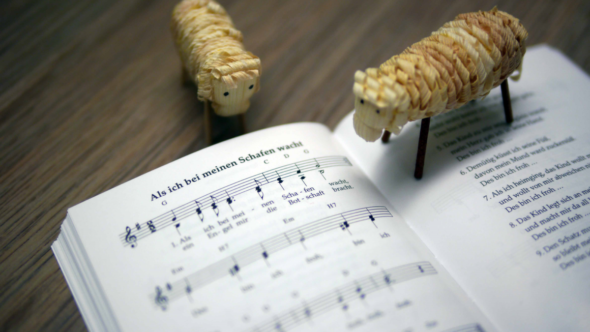Zwei Schaf-Figuren und ein aufgeschlagenes Notenblatt. "Als ich bei meinen Schafen wacht".