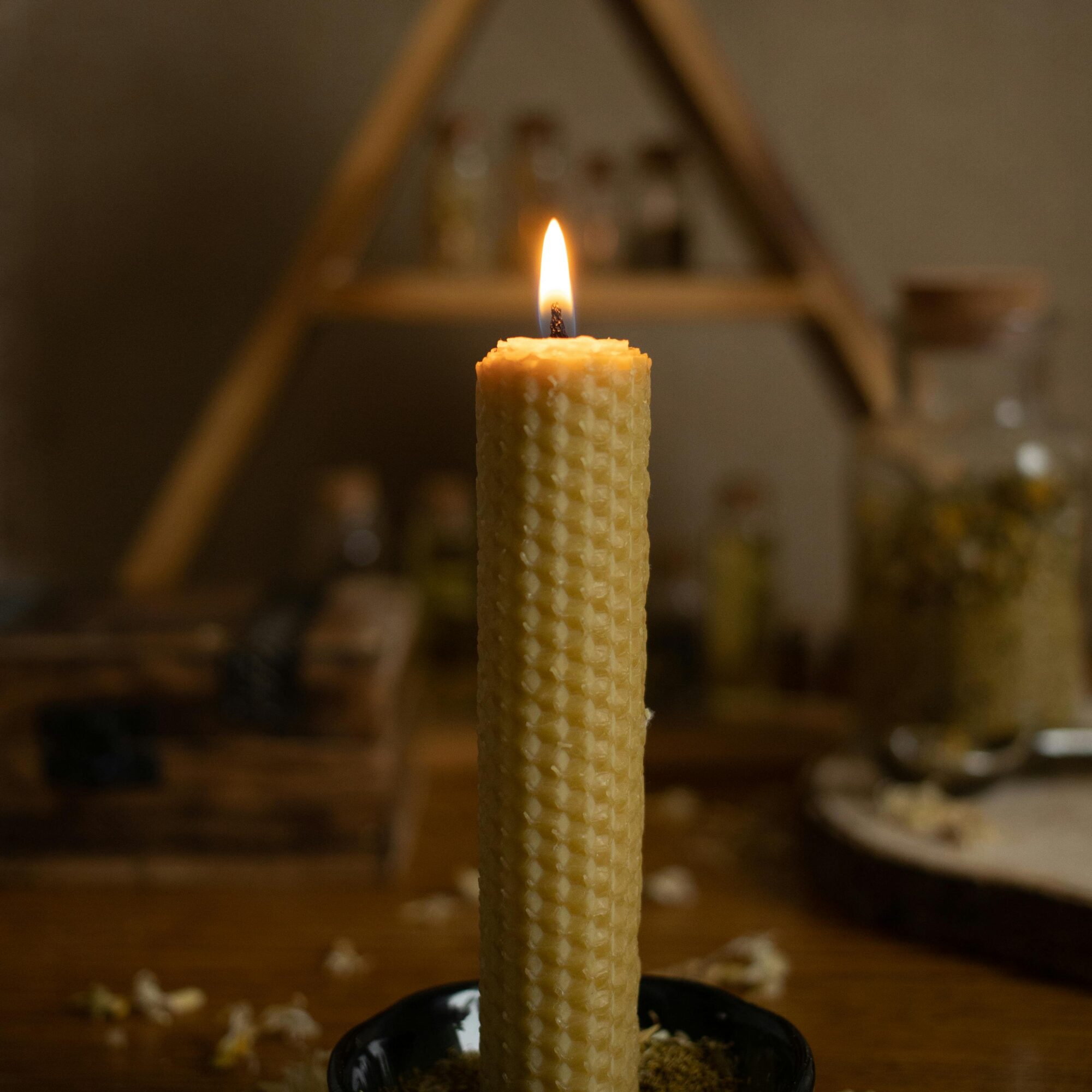 Nahaufnahme einer Kerze mit Wabenmuster in einer schwarzen Schale.