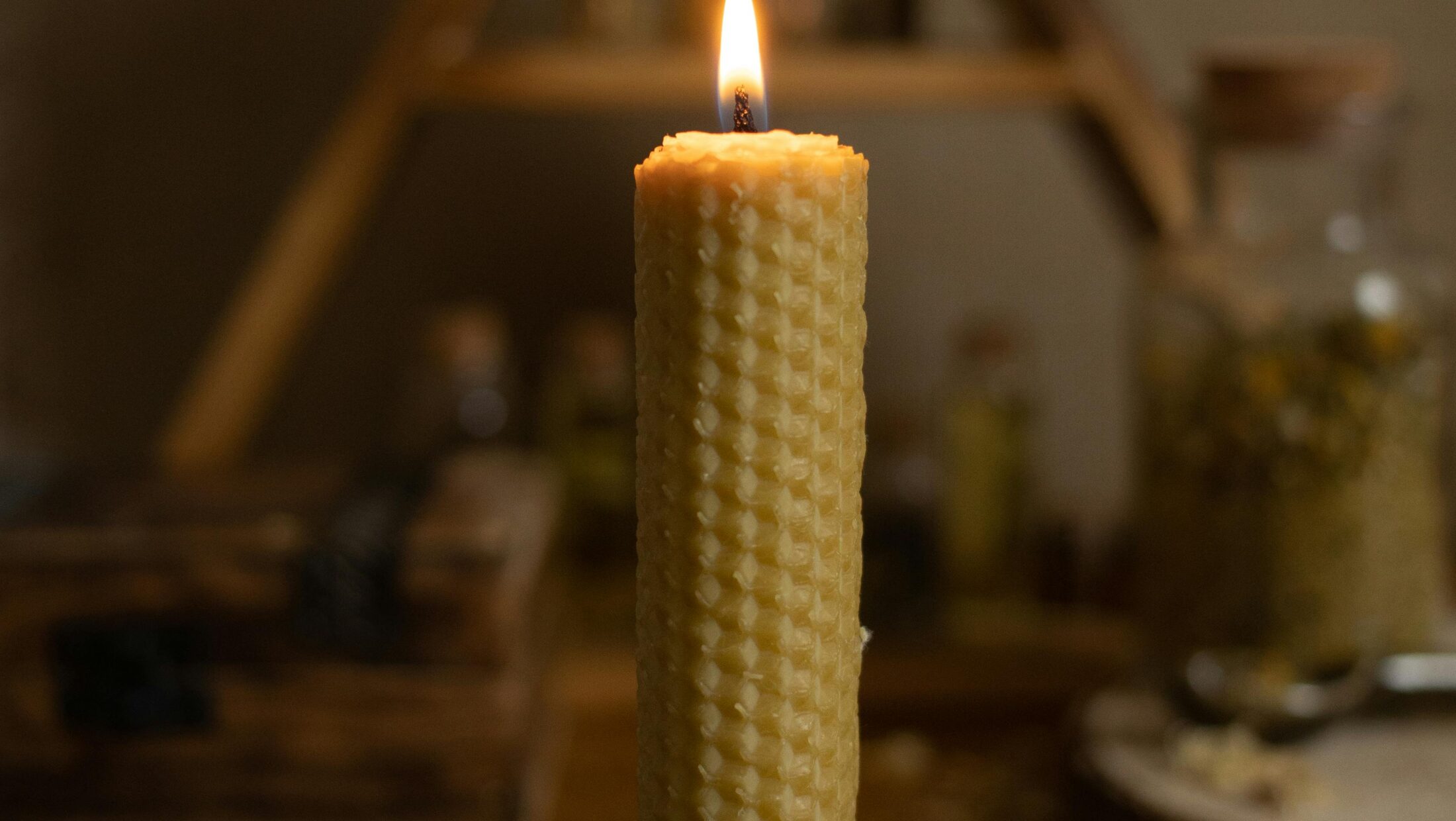 Nahaufnahme einer Kerze mit Wabenmuster in einer schwarzen Schale.