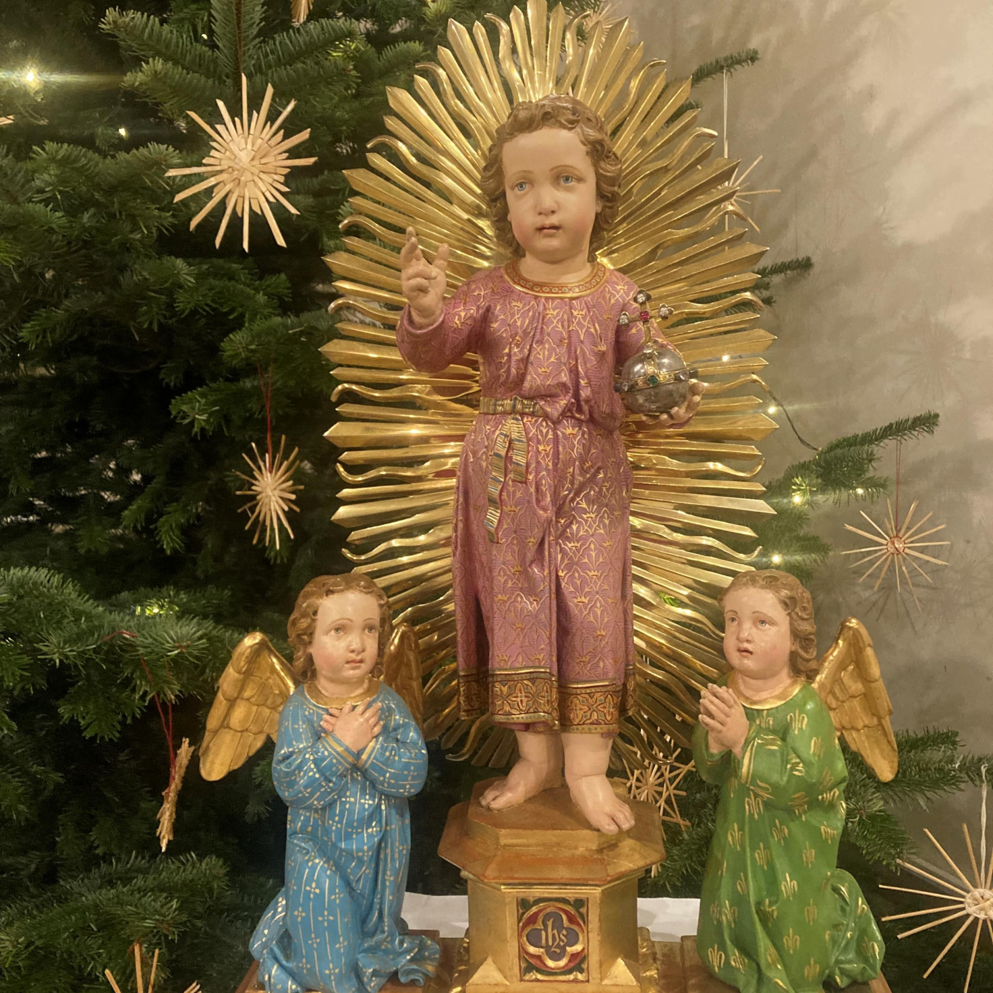Jesuskind-Statue mit Engeln und Christbaum.
