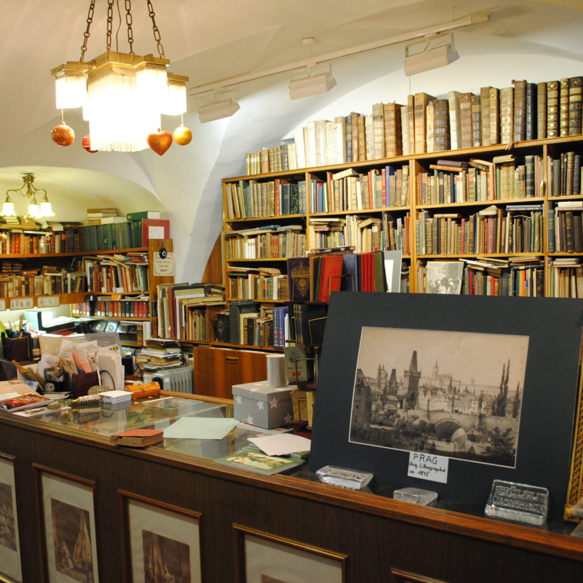 Innenraum des Buchladens; Bücherregale mit alten Büchern, Text: PRAG.