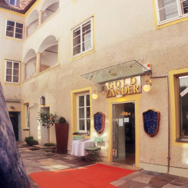 Hof von Gold Zander in Graz mit Steinskulptur und Tisch.
