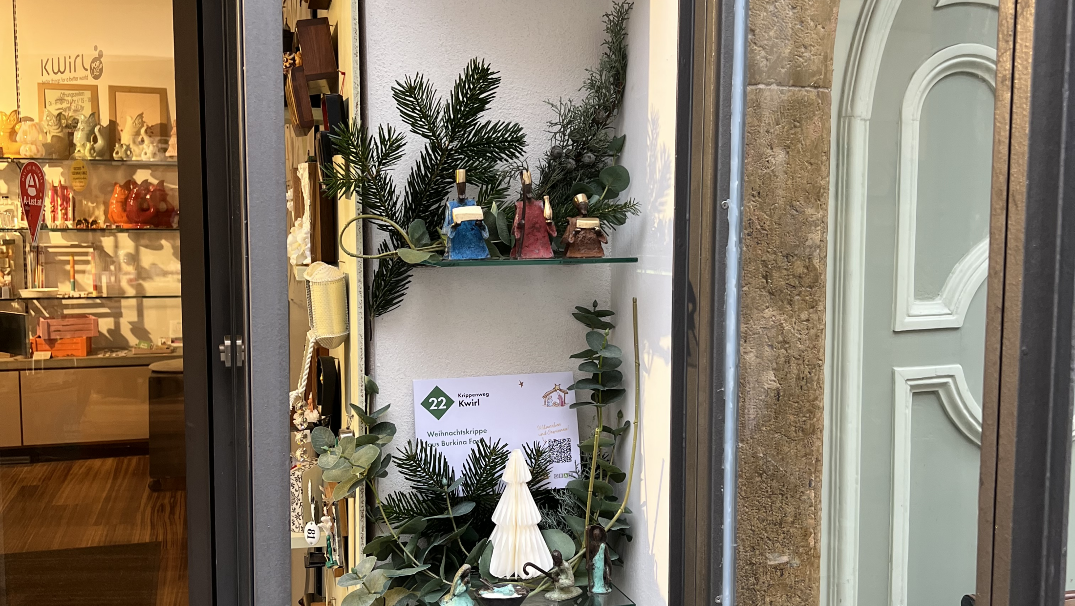 Schaufenster von Kwirl in Graz zeigt Weihnachtsdeko auf Glasregalen.
