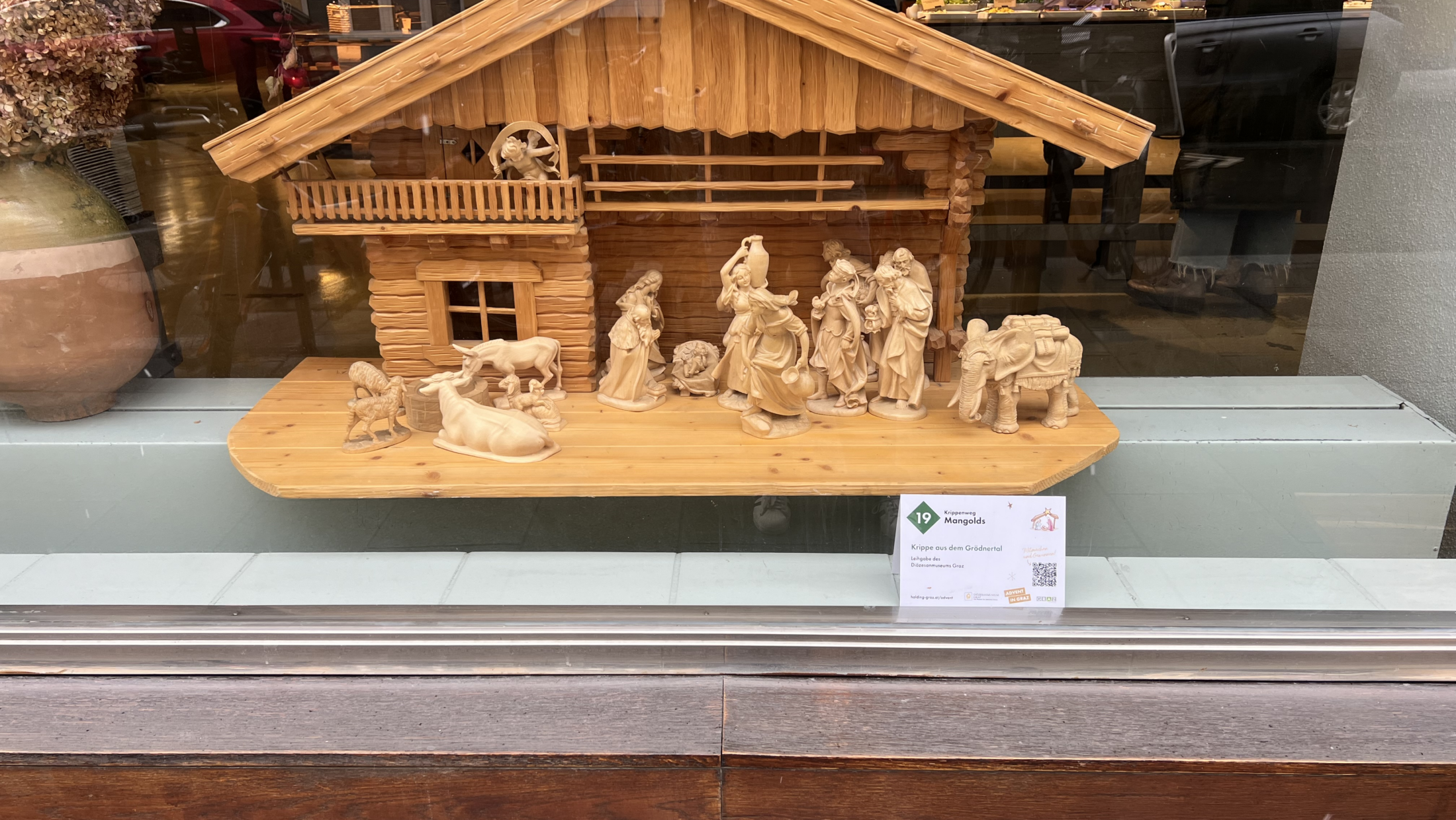 Hölzerne Krippe aus dem Gröbacher mit Schild „Krippe aus dem Gröbacher“.
