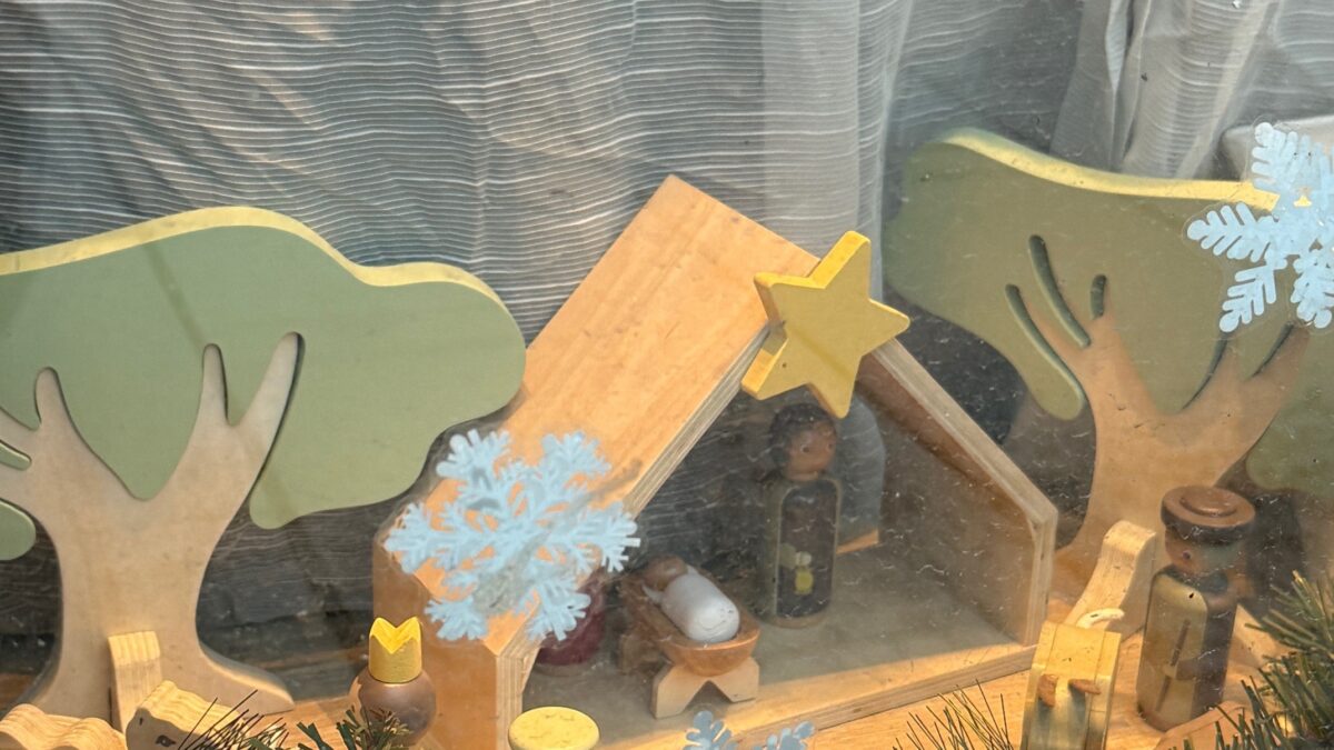 Hölzerne Krippe mit Baum, Stern und Schneeflocken.