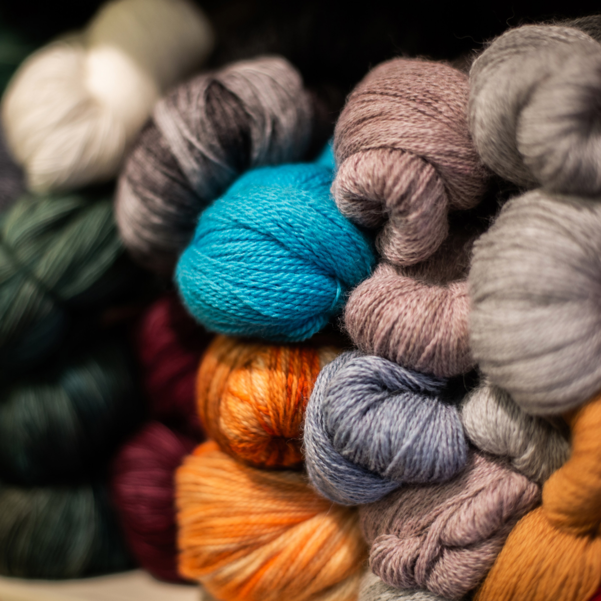 Ein Stapel bunter Wollknäuel, einige davon sind unscharf.