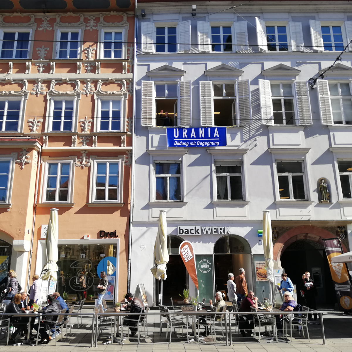 Straßenszene in Graz mit Cafés, "URANIA" und "backWERK".