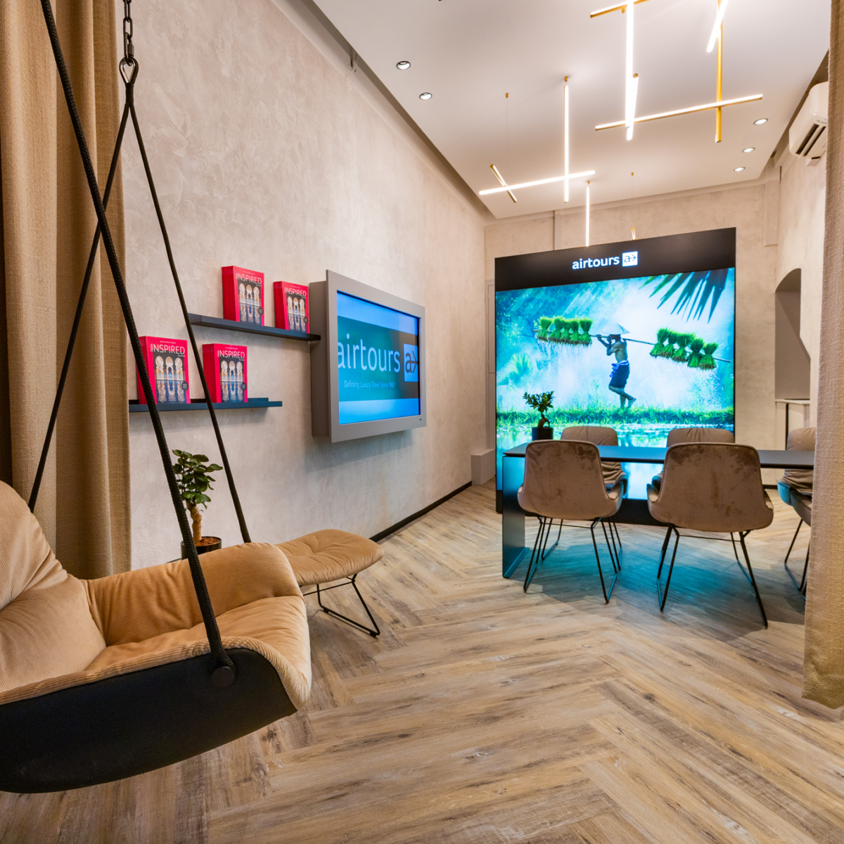 Modernes Interieur mit "airtours"-Bildschirmen, Schaukelstuhl und Besprechungsraum.