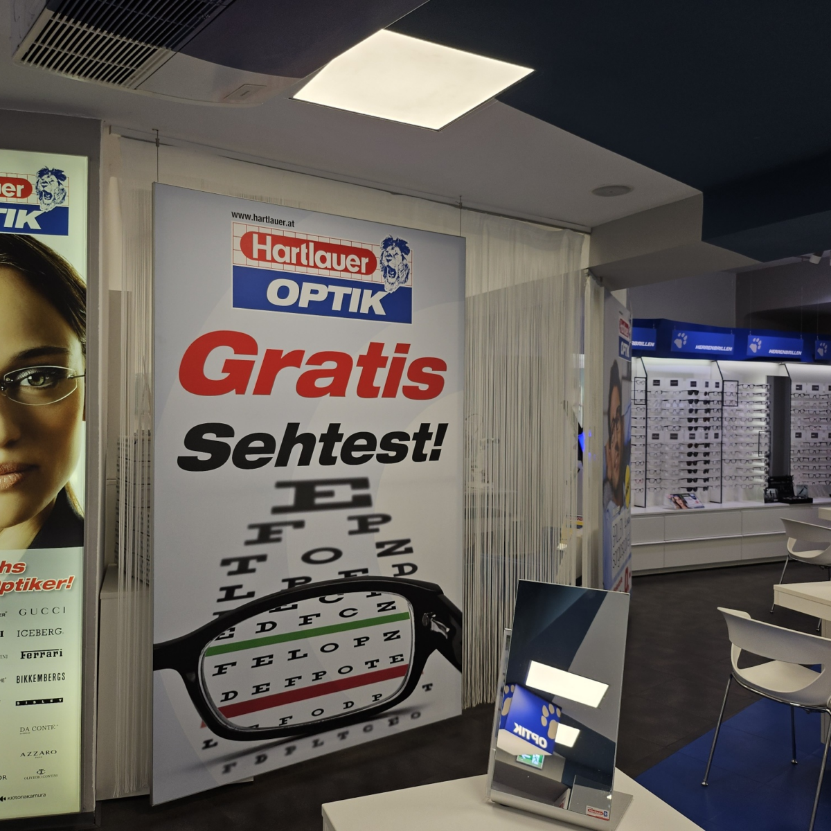 Innenraum von Hartlauer Optik mit "Gratis Sehtest!"-Schild.