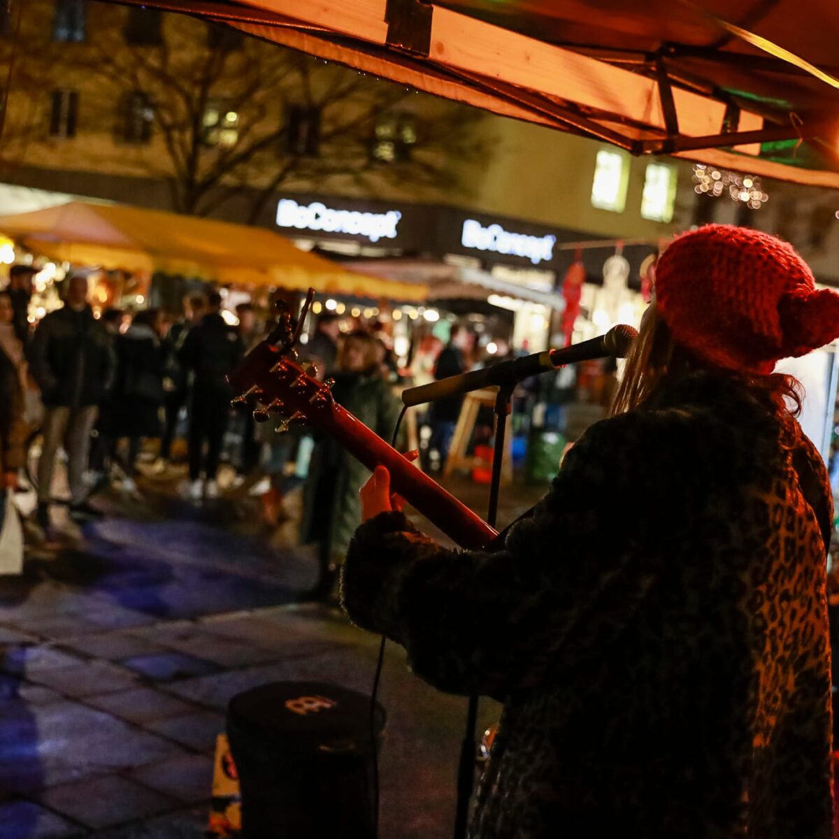 Eine Frau spielt Gitarre auf einem Markt in Graz.