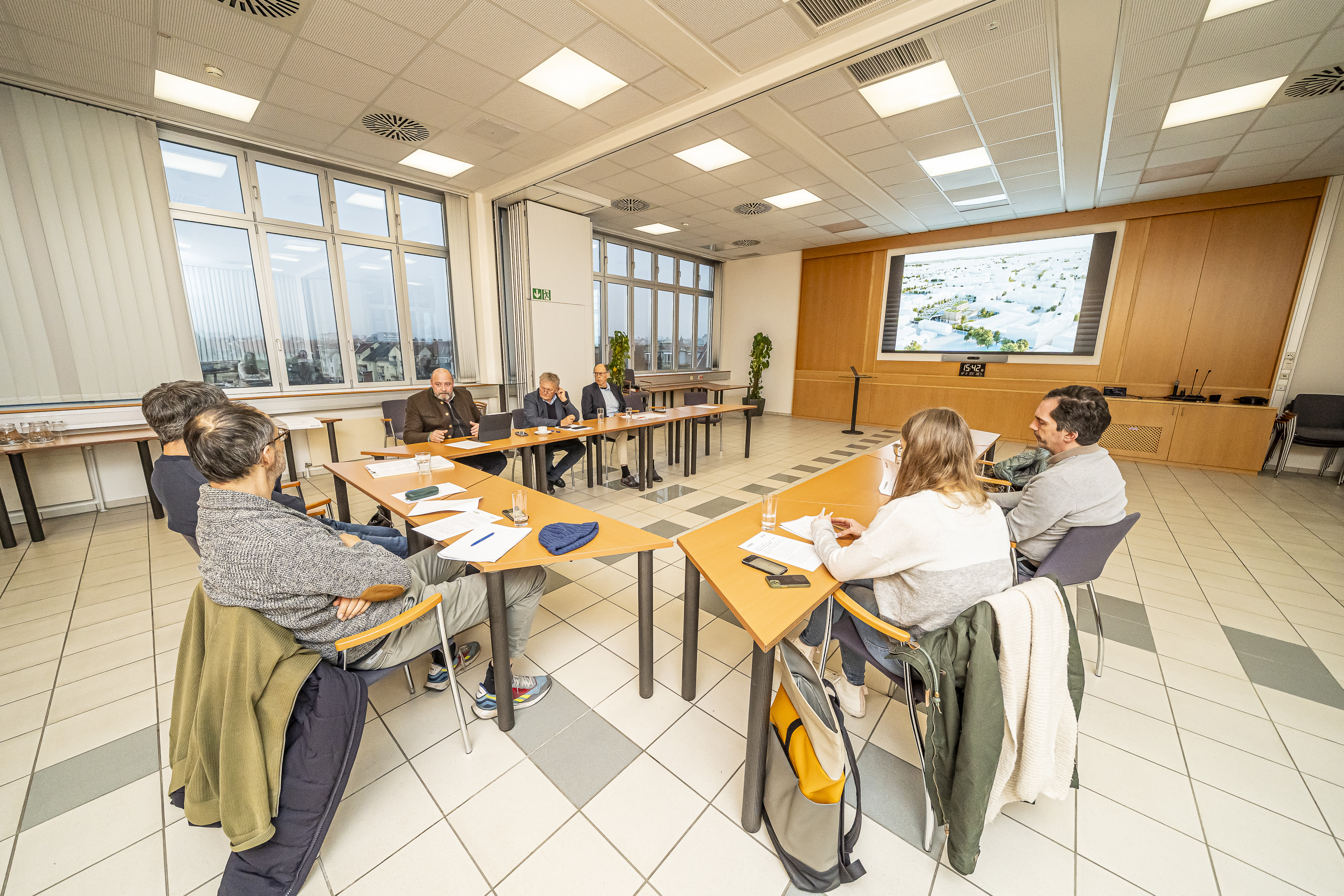 Besprechungsraum mit Personen an Tischen, Präsentation an der Wand, Graz.