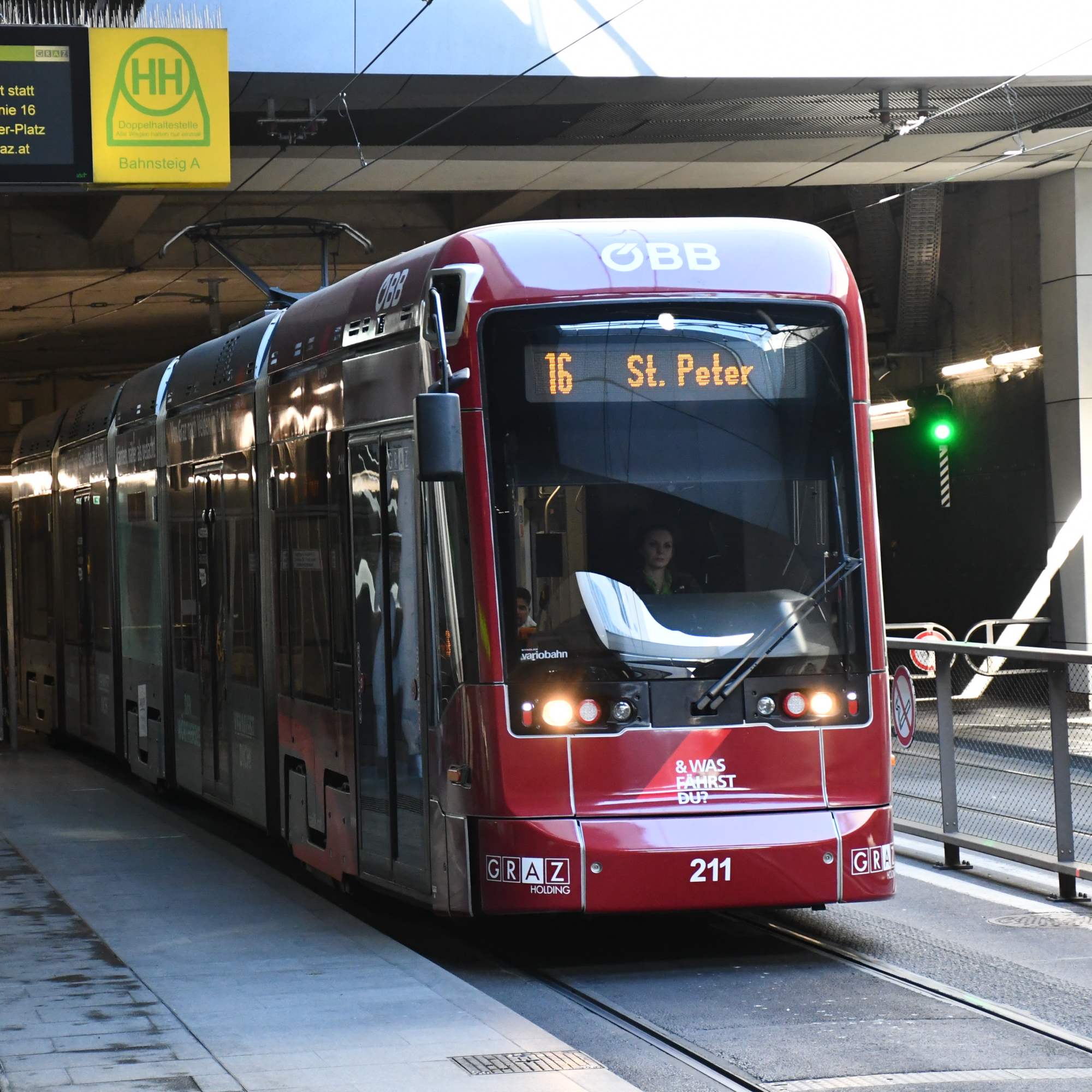Eine rote ÖBB-Straßenbahn der Linie 16 nach St. Peter in Graz am Bahnsteig A.