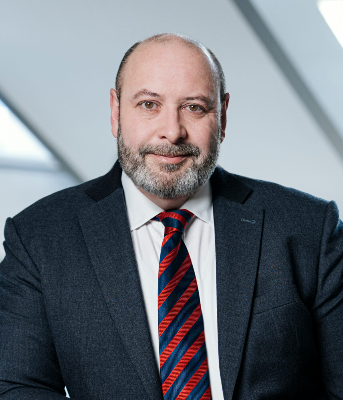 Porträt eines Mannes mit Bart, Anzug und Krawatte.