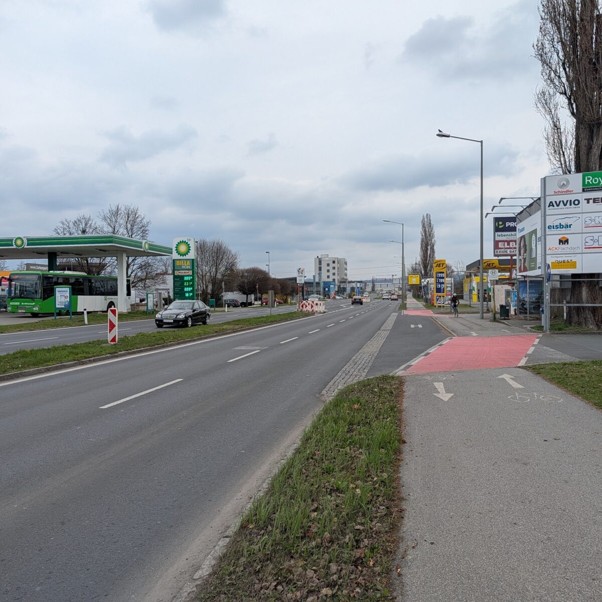 Eine Straße in Graz mit einer BP-Tankstelle und Werbetafeln.
