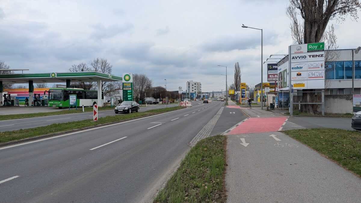 Eine Straße in Graz mit einer BP-Tankstelle und Werbetafeln.