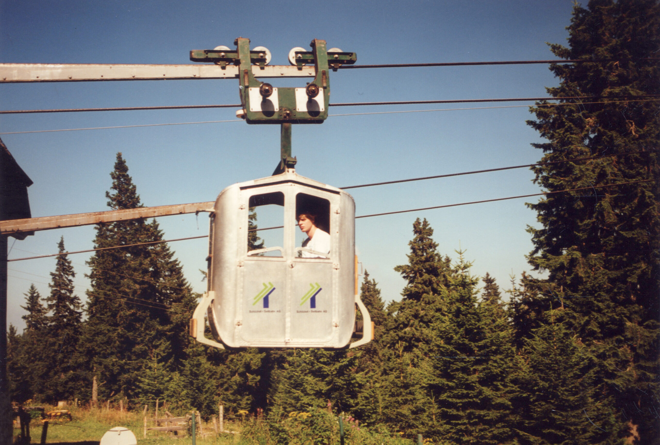 Eine Gondel der Schlossbergbahn Graz, mit einer Person, umgeben von Bäumen.