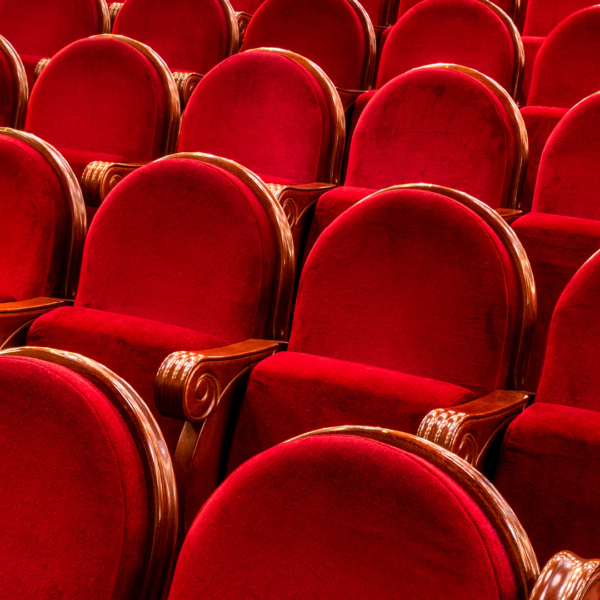 Viele rote Samtsitze mit Holzrahmen in einem Theater oder Kino.