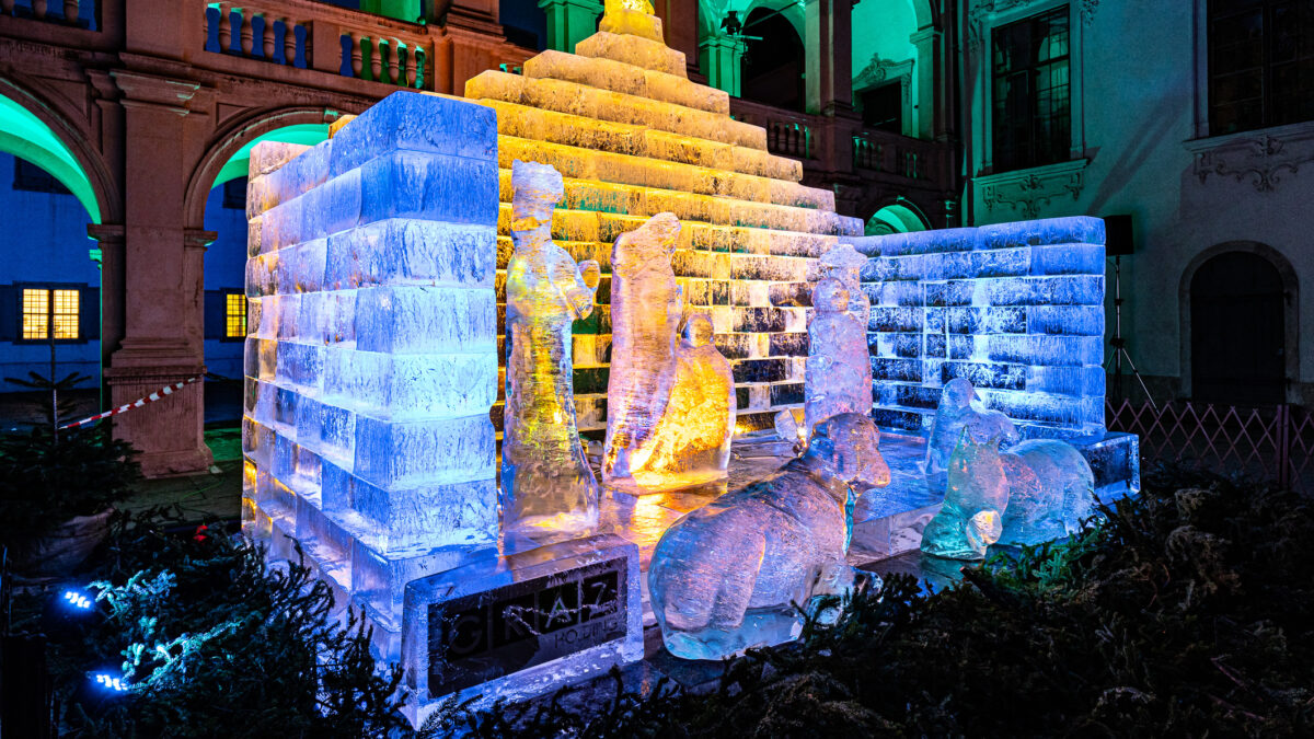 Bunt beleuchtete Eiskrippe im Landhaushof in Graz bei Nacht.