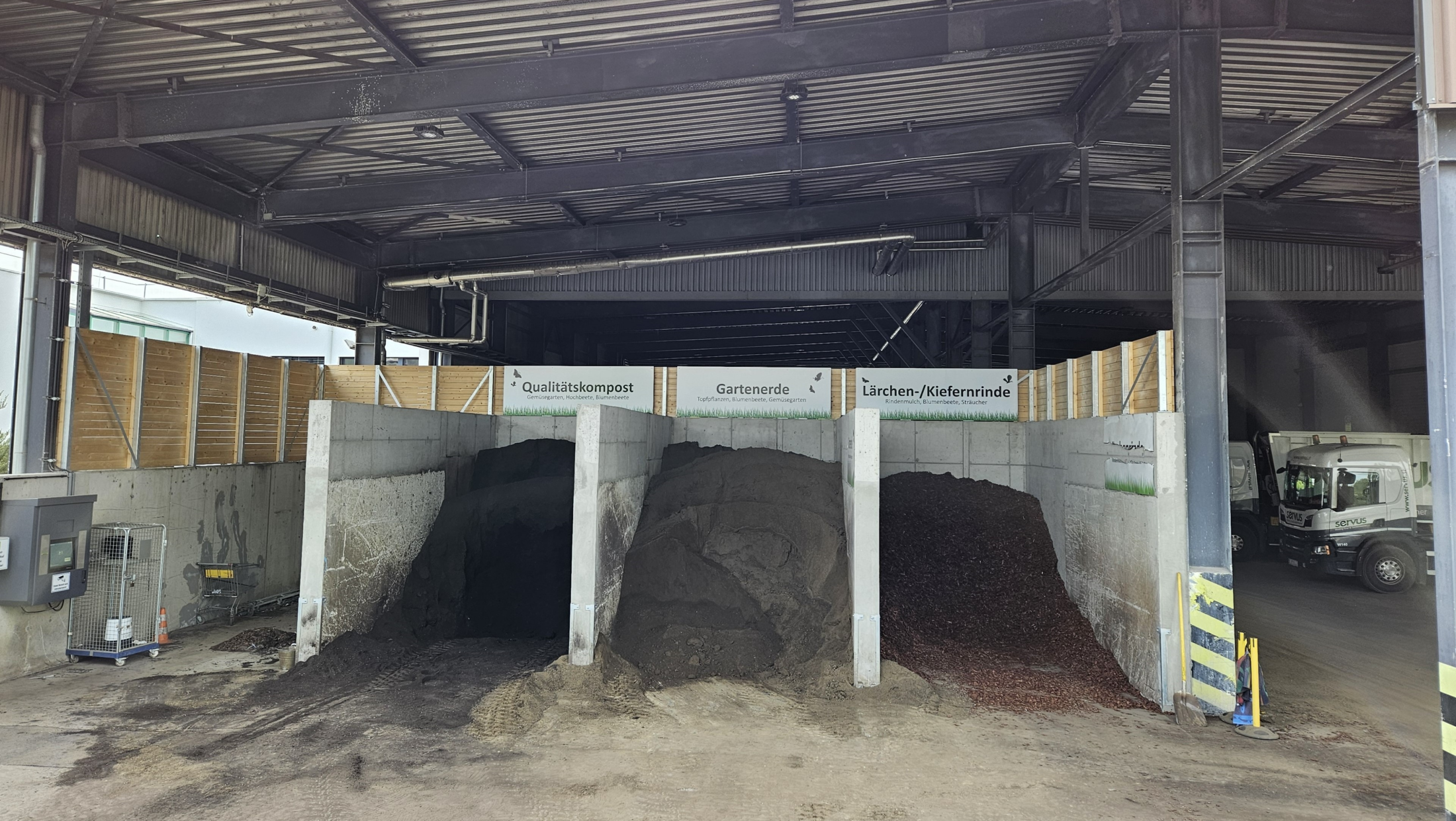Kompostieranlage mit drei großen Haufen aus Qualitätskompost, Gartenerde und Lärchen-/Kiefernrinde, LKW im Hintergrund