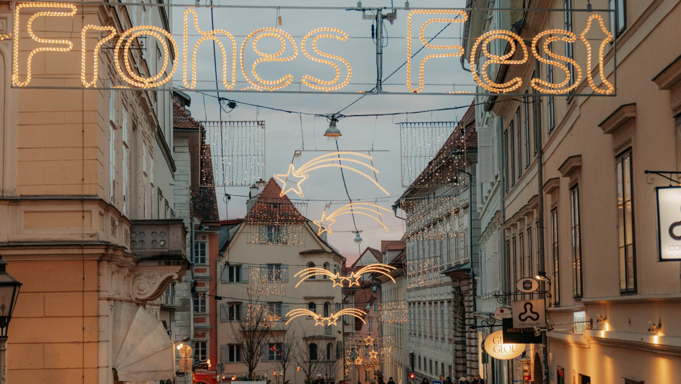 Weihnachtsbeleuchtung mit der Aufschrift „Frohes Fest“ in einer Gasse in Graz.