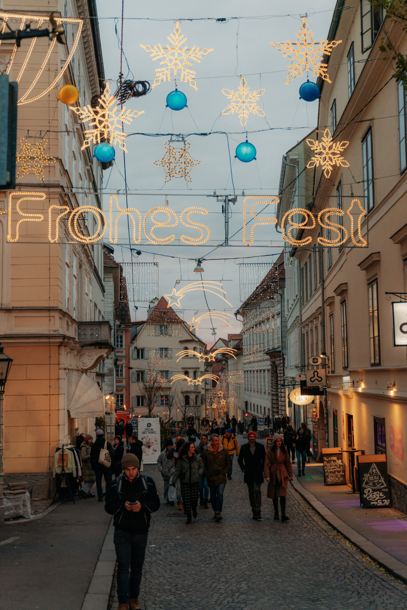 Christmas lights and "Frohes Fest" sign over a street in Graz.